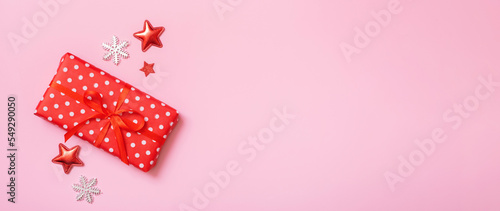 Banner with Christmas present flat lay on a pink background. Top view xmas gift box with decorations. Copy space
