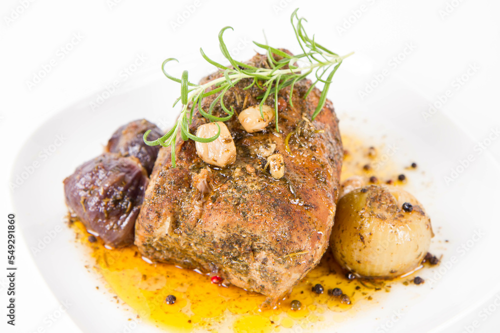 Roast pork loin with onions and garlic, decorated with rosemary and some colorful peppercorns