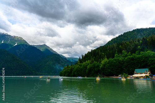 Alpine Lake Ritsa. Tourists on catamaran sailing along lake among mountains. © Evgeniy