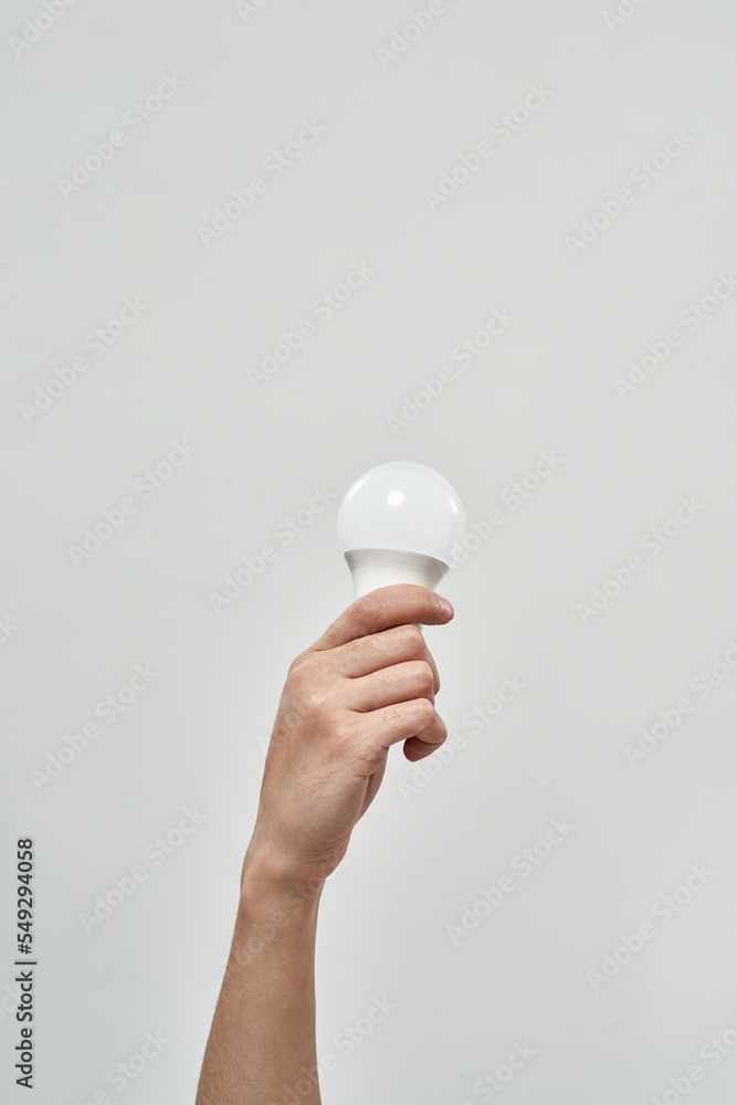 Partial male hand holding lightbulb on white Partial male hand holding lightbulb on white