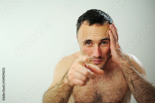 Adult handsome man with beard background happy face smiling with crossed arms looking at the camera. Positive person A man with a naked torso and hairy arms With one hand held at the temple on head photo