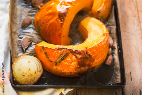 Roasted pumpkin with onion and garlic on baking tray. Preparing pumpkin soup