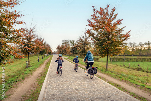An autumn park cycling trip with the family. Mom and two children on bicycles. Autumn landscape