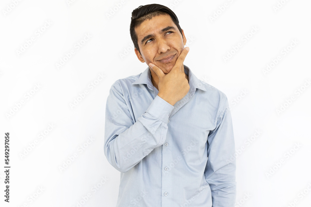 Handsome man thinking hard while standing on white background. Pensive Hispanic man touching his chin, looking up, considering ideas. Contemplation, planning, concentration concept Handsome man thinking hard while standing on white background. Pensive Hispanic man touching his chin, looking up, considering ideas. Contemplation, planning, concentration concept