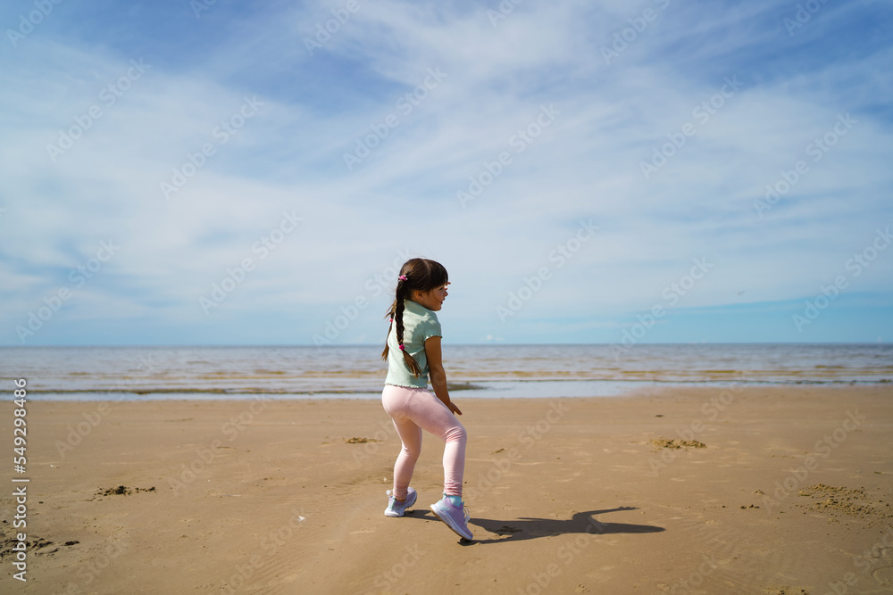 Little girl dancing on the beach in summer.