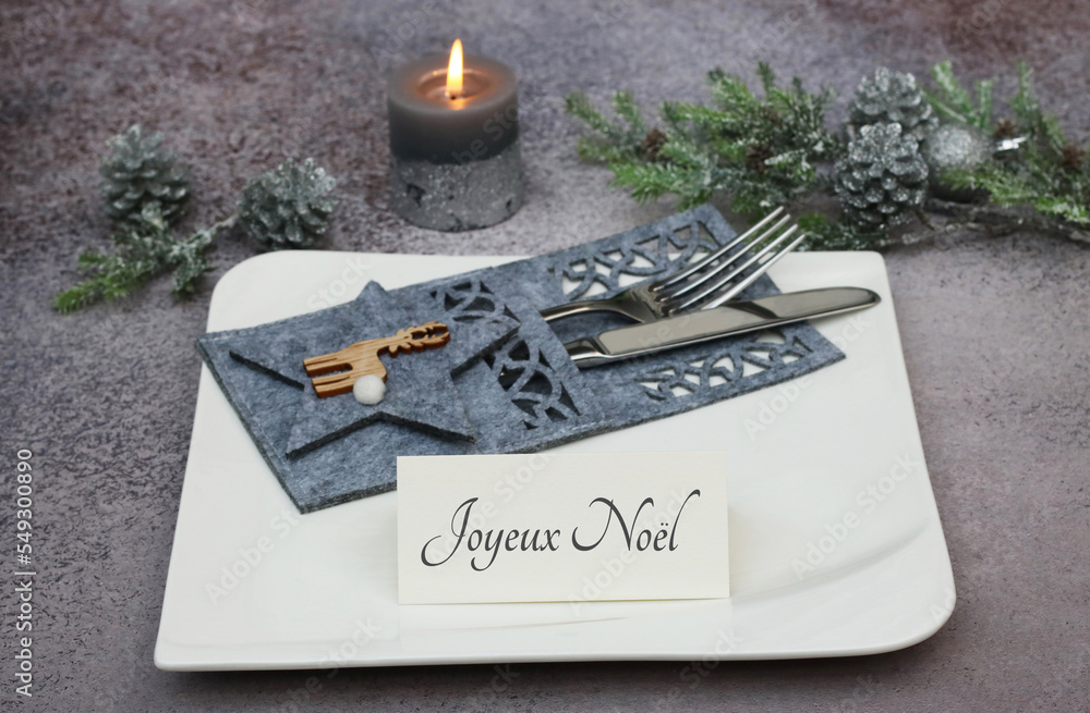 Table de Noël festive avec assiette et couverts. Message de Noël sur