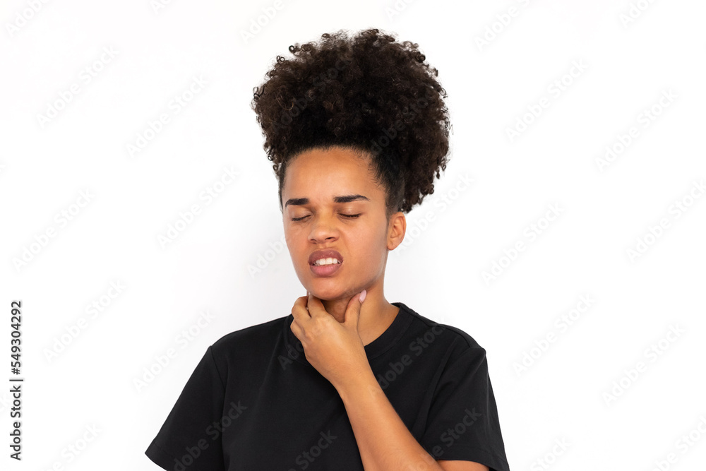 Portrait of displeased young woman touching neck against white background. African American woman wearing black T-shirt suffering from sore throat. Pulmonary diseases concept Portrait of displeased young woman touching neck against white background. African American woman wearing black T-shirt suffering from sore throat. Pulmonary diseases concept
