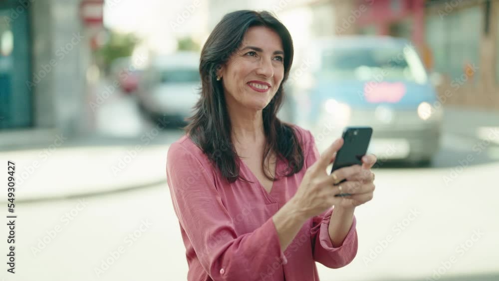 Middle age hispanic woman smiling confident using smartphone at street Middle age hispanic woman smiling confident using smartphone at street