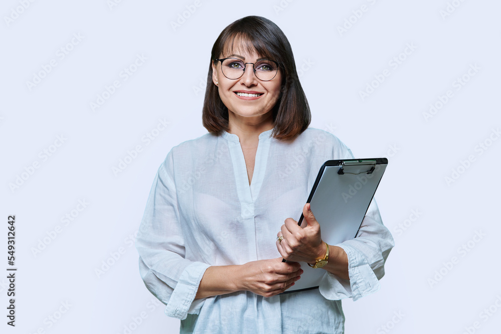 Middle aged business woman with clipboard looking at camera on white background Middle aged business woman with clipboard looking at camera on white background