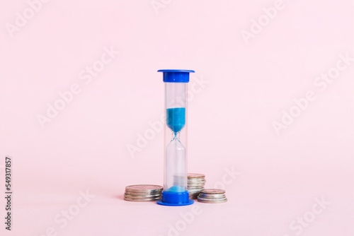 Deadline and time is money concept with hourglass and US coins currency. sand clock time for saving concept