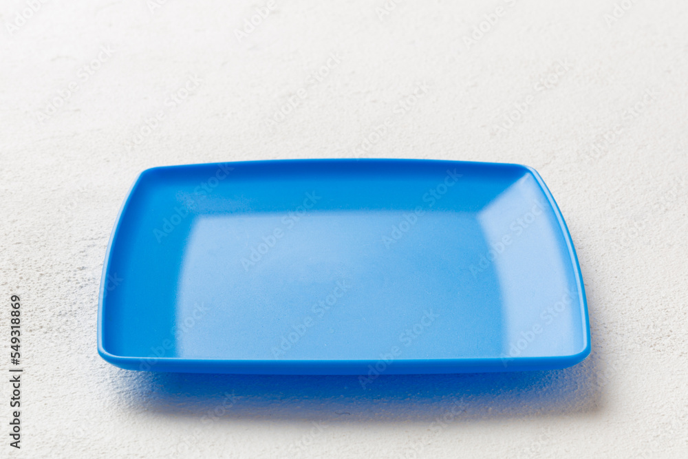 Perspective view of empty square plate on cement background. Empty space for your design Perspective view of empty square plate on cement background. Empty space for your design