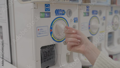 This close up video shows a hand inserting money, turning the knob, and getting a surprise toy from a capsule vending machine.