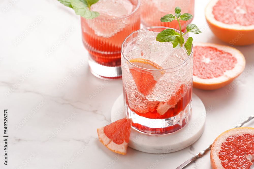 Preparation of a grapefruit alcohol free cocktail - several tumbler glasses with ice cubes on marble surface with fresh mint Preparation of a grapefruit alcohol free cocktail - several tumbler glasses with ice cubes on marble surface with fresh mint