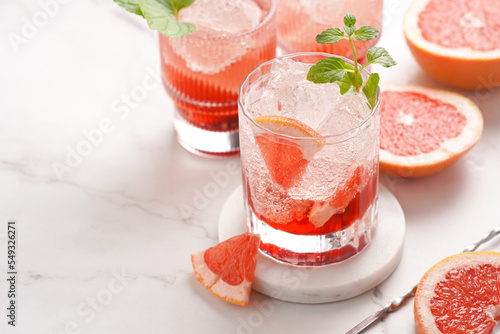 Preparation of a grapefruit alcohol free cocktail - several tumbler glasses with ice cubes on marble surface with fresh mint © Romana