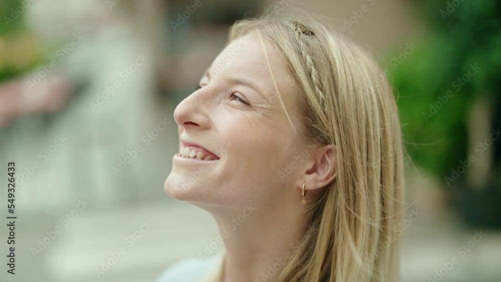 Young blonde woman smiling confident looking to the sky at street Young blonde woman smiling confident looking to the sky at street