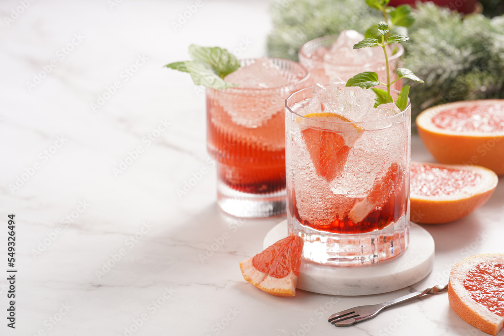 Preparation of a grapefruit alcohol free cocktail - several tumbler glasses with ice cubes on marble surface with fresh mint Preparation of a grapefruit alcohol free cocktail - several tumbler glasses with ice cubes on marble surface with fresh mint