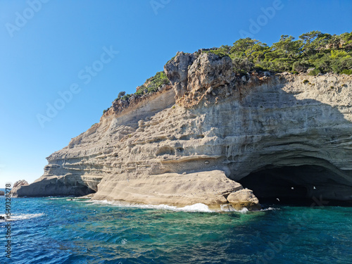 22 Oct 2022, Kemer, Antalya, Turkey. Boat trip, close to the cliff with a cave inside. Cave is called Pirate Cave. Plans on top of the cliff, blue sea, birds, blue sky, perfect landscape.