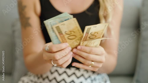 Young woman counting brazil real banknotes at home photo