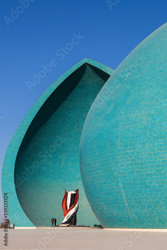 Baghdad, Iraq - November 2022: Split turquoise domes of Al Shaheed war memorial also called as Martyr's monument at the centre of the two half-domes is the Iraqi flag photo