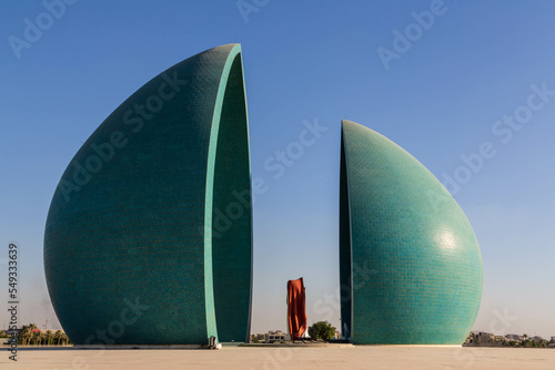 Baghdad, Iraq - November 2022: Split turquoise domes of Al Shaheed war memorial also called as Martyr's monument at the centre of the two half-domes is the Iraqi flag photo