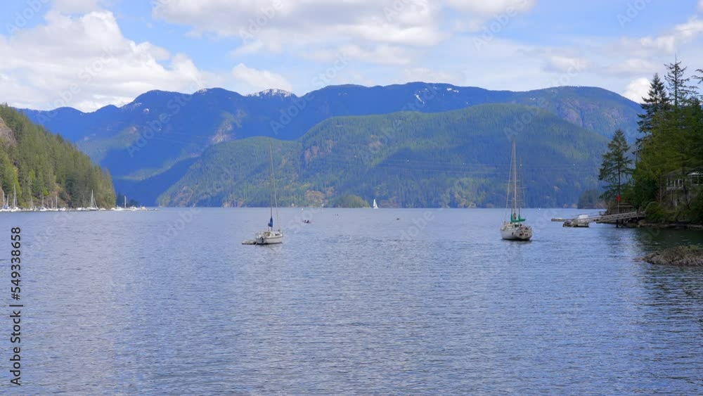 Establishing shot of ocean view with mountains, blue sky and white clouds in slow motion at summer day in Vancouver, Canada, North America. Day time on September 2021. Still camera. ProRes 422 HQ. Establishing shot of ocean view with mountains, blue sky and white clouds in slow motion at summer day in Vancouver, Canada, North America. Day time on September 2021. Still camera. ProRes 422 HQ.