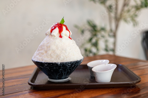 Korean shaved ice dessert with sweet toppings, Strawberry Bingsu on wood table