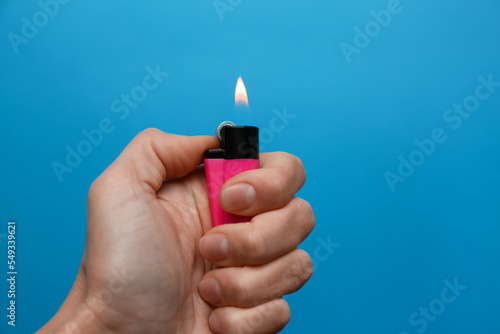Woman holding pink lighter on light blue background, closeup