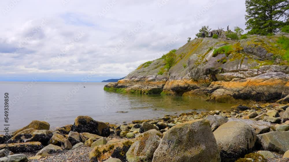 Establishing aerial shot of ocean beach with rocks and pebbles in slow motion at summer day in Vancouver, Canada, North America. Day time on September 2022. Drone forward. ProRes 422 HQ. Establishing aerial shot of ocean beach with rocks and pebbles in slow motion at summer day in Vancouver, Canada, North America. Day time on September 2022. Drone forward. ProRes 422 HQ.