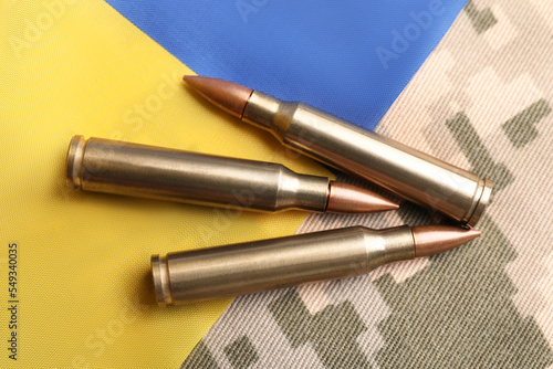 Bullets and Ukrainian flag on military camouflage, flat lay