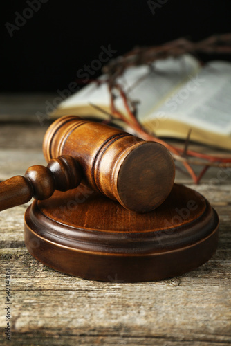 Judge gavel on old wooden table against black background, closeup