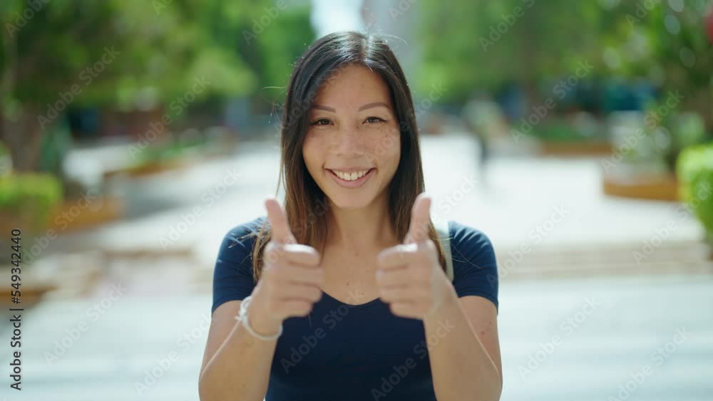 Young asian woman smiling confident doing ok sign with thumbs up at street Young asian woman smiling confident doing ok sign with thumbs up at street