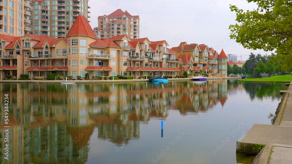 Establishing shot of modern apartment building with balcony, trees and beautiful water landscape in Vancouver, Canada, North America. Day time on March 2022. ProRes 422 HQ. Establishing shot of modern apartment building with balcony, trees and beautiful water landscape in Vancouver, Canada, North America. Day time on March 2022. ProRes 422 HQ.