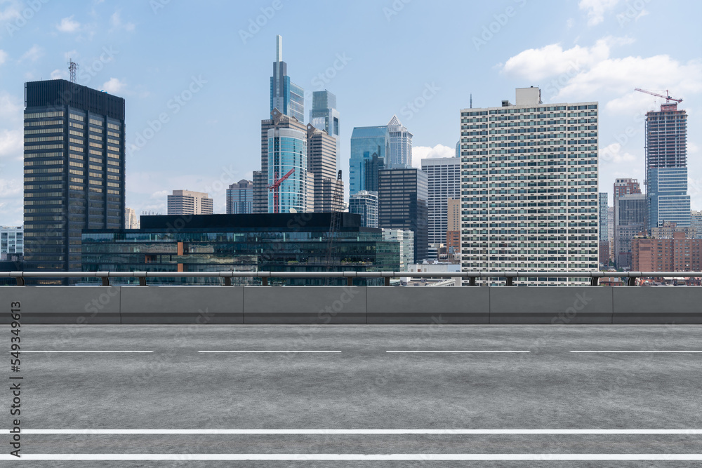 Empty urban asphalt road exterior with city buildings background. New modern highway concrete construction. Concept way to success. Transportation logistic industry fast delivery. Philadelphia. USA. Empty urban asphalt road exterior with city buildings background. New modern highway concrete construction. Concept way to success. Transportation logistic industry fast delivery. Philadelphia. USA.