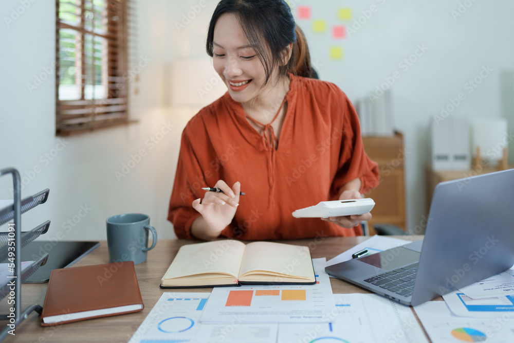 Portrait of a thoughtful Asian businesswoman looking at financial statements and making marketing plans using a computer on her desk Portrait of a thoughtful Asian businesswoman looking at financial statements and making marketing plans using a computer on her desk