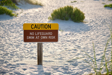 Warning sign poster on sea side beach saying that there is no lifeguard on duty