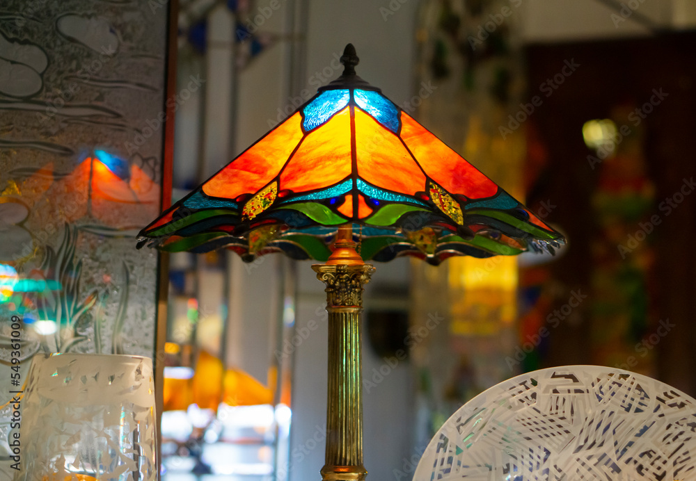 Multi color glass lamp . Interesting interior. Tiffany lamp on wooden  table. Stained glass lamp, with a lampshade of colourful glass mosaic in  green, yellow and red. Stock Photo | Adobe Stock