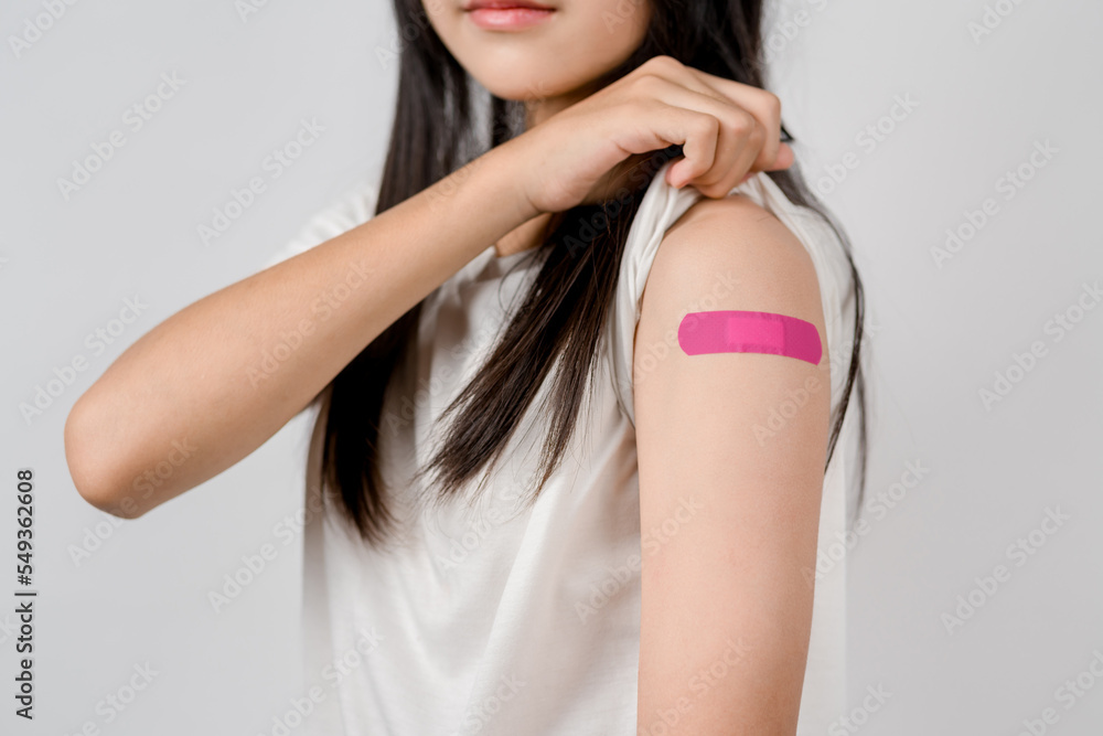Happy young woman after getting a vaccine. showing shoulder arm with bandage after receiving vaccination, herd immunity, side effect, booster dose, vaccine passport and Coronavirus pandemic Happy young woman after getting a vaccine. showing shoulder arm with bandage after receiving vaccination, herd immunity, side effect, booster dose, vaccine passport and Coronavirus pandemic