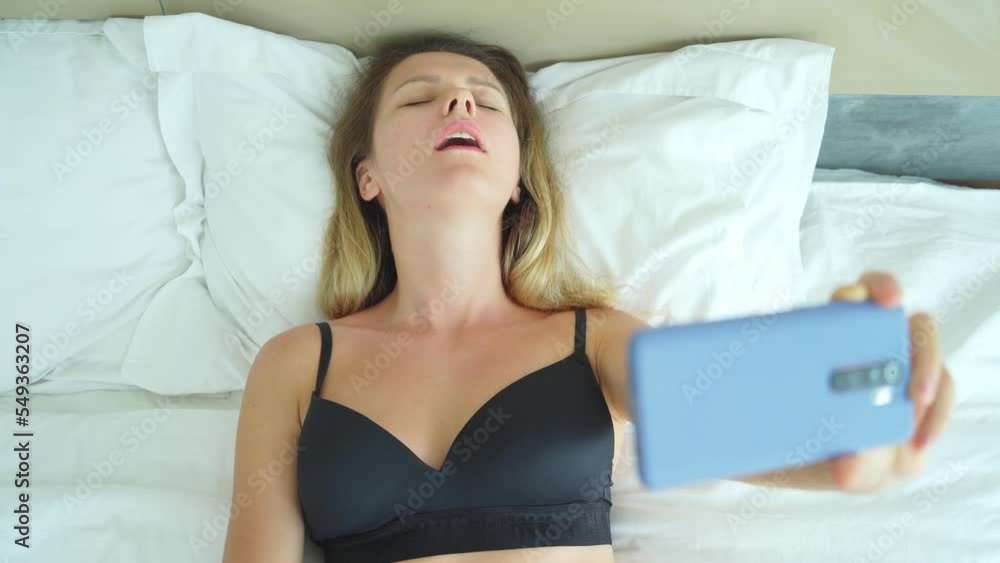 Young woman posing in front of smartphone in his hand and working webcam model Young woman posing in front of smartphone in his hand and working webcam model