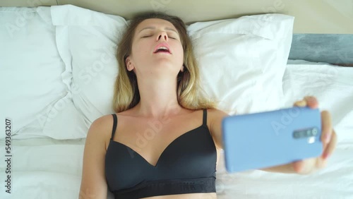 Young woman posing in front of smartphone in his hand and working webcam model photo