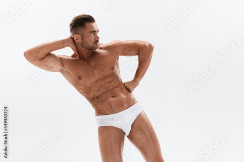 Man athletic body bodybuilder in briefs with naked torso abs full-length in the background, fitness classes. Advertising, sports, active lifestyle, competition, challenge concept. © SHOTPRIME STUDIO