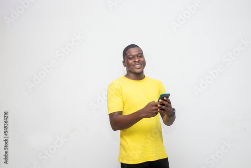 Handsome young southAfrican guy using cellphone, surfing web or social media, looking at camera isolated over a white studio background photo