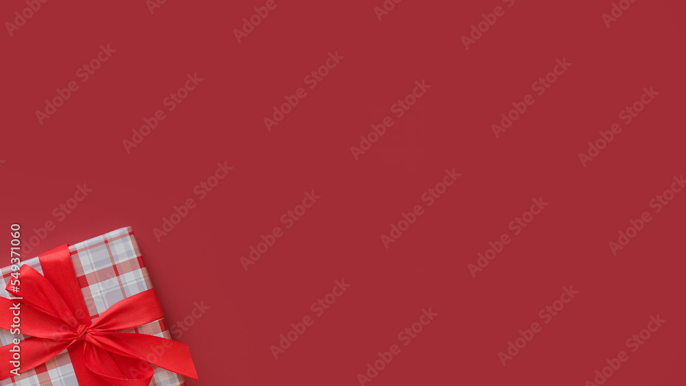 Square gift box with a red bow on a red background top view with a place for text Square gift box with a red bow on a red background top view with a place for text