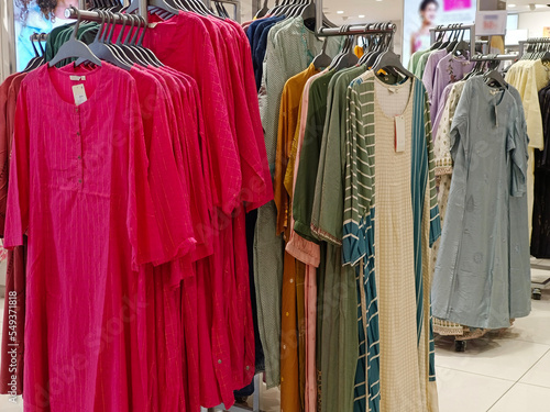Female casual clothes in boutique, clothes with a selection of ladies fashion, Colorful women's dresses on hangers in a retail shop in India.