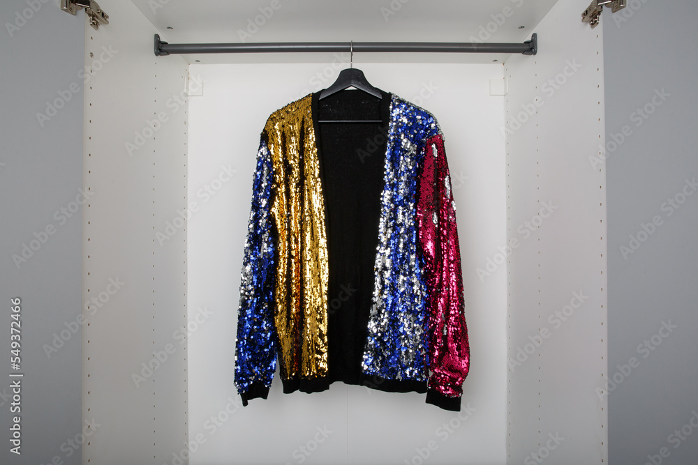 single multicoloured sequin party cardigan on clothes rail in empty white wardrobe or closet