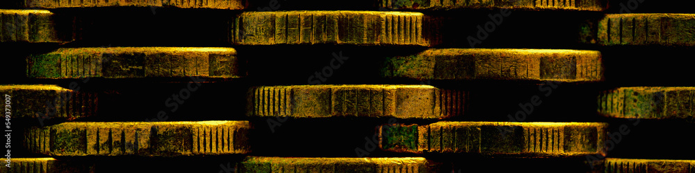 Naklejka premium Stacks of coins close-up. Money textured header. Dark brown abstract banner made of many coin edges. Image with high contrast and saturation. Economy finance and banking. Macro