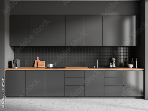 Front view on dark kitchen room interior with grey wall