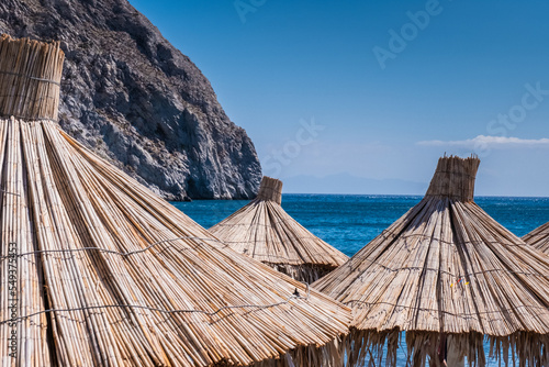 Beach on the Greek island of Santorini with sunbeds and umbrellas. 