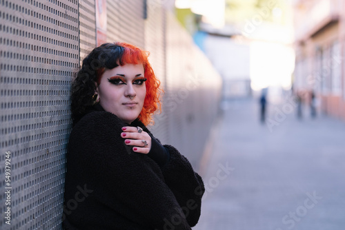 Portrait of a young transgender woman with dyed orange hair.