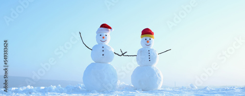 Couple of two snowman holding hands outdoors. Snowman on the snow outdoor background. Christmas banner with snowman. New year greeting card with with snowman. photo