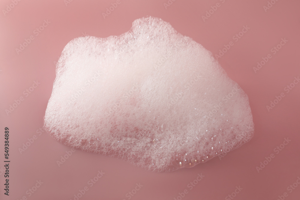 Fototapeta premium Fluffy bath foam on pink background, top view